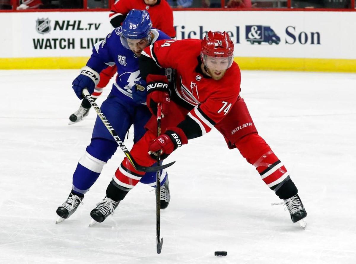The Canes' Jaccob Slavin (74) and the Lightning's Cory Conacher (89) go for the puck during the first period.