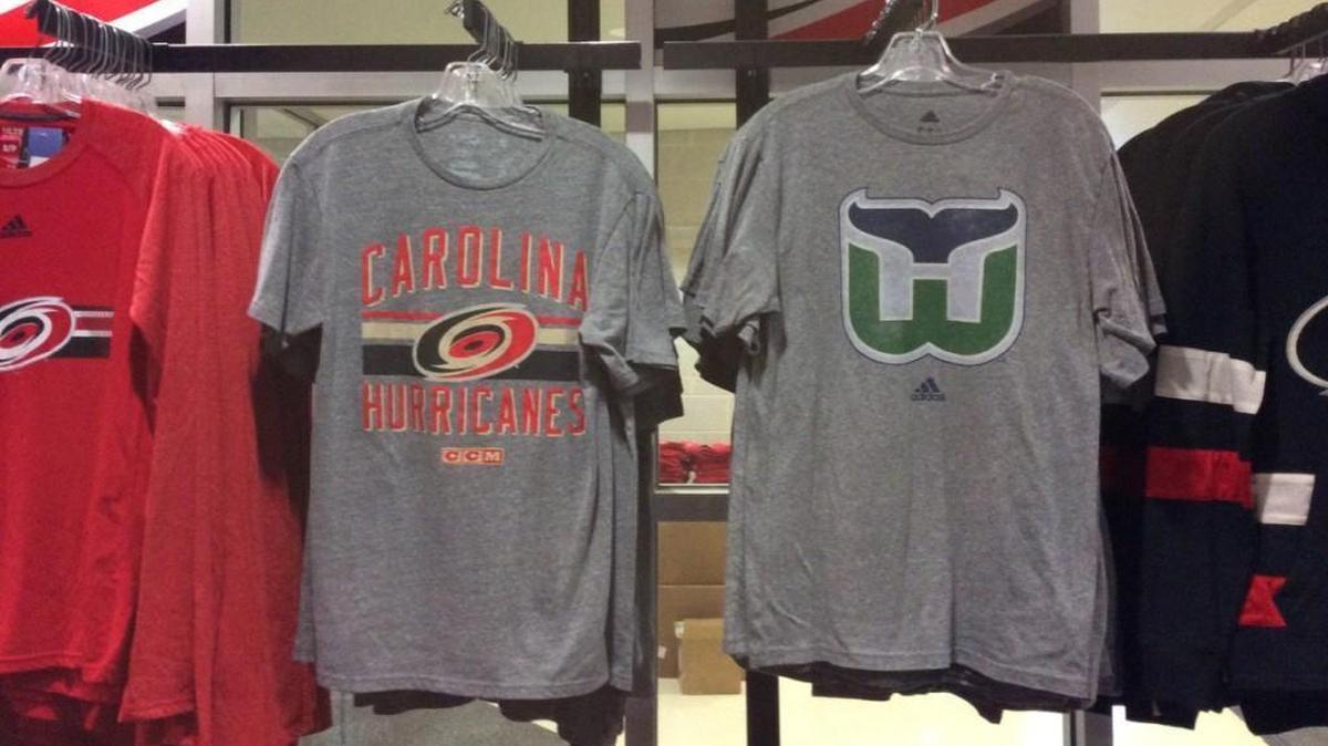 A Hartford Whalers T-shirt hangs next to a Carolina Hurricanes T-shirt at PNC Arena. The Whalers moved from Connecticut to Raleigh and became the Carolina Hurricanes in 1997.