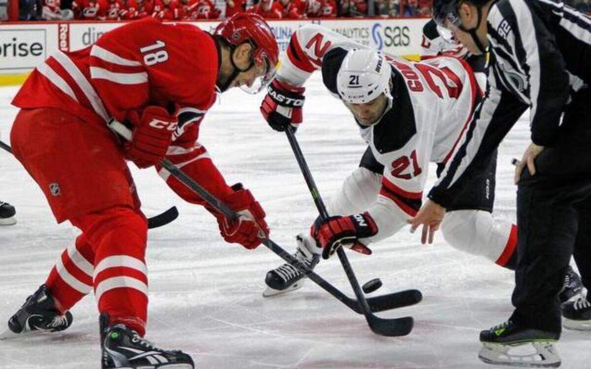 
The Carolina Hurricanes’ Jay McClement (18) faces off against New Jersey’s Scott Gomez (21) during a game at PNC Arena in Raleigh on Dec. 8. The NHL’s general managers approved a proposal from Hurricanes GM Ron Francis mandating that defensive players on the defensive side of the red line must put their sticks to the ice before the puck is dropped on faceoffs.
