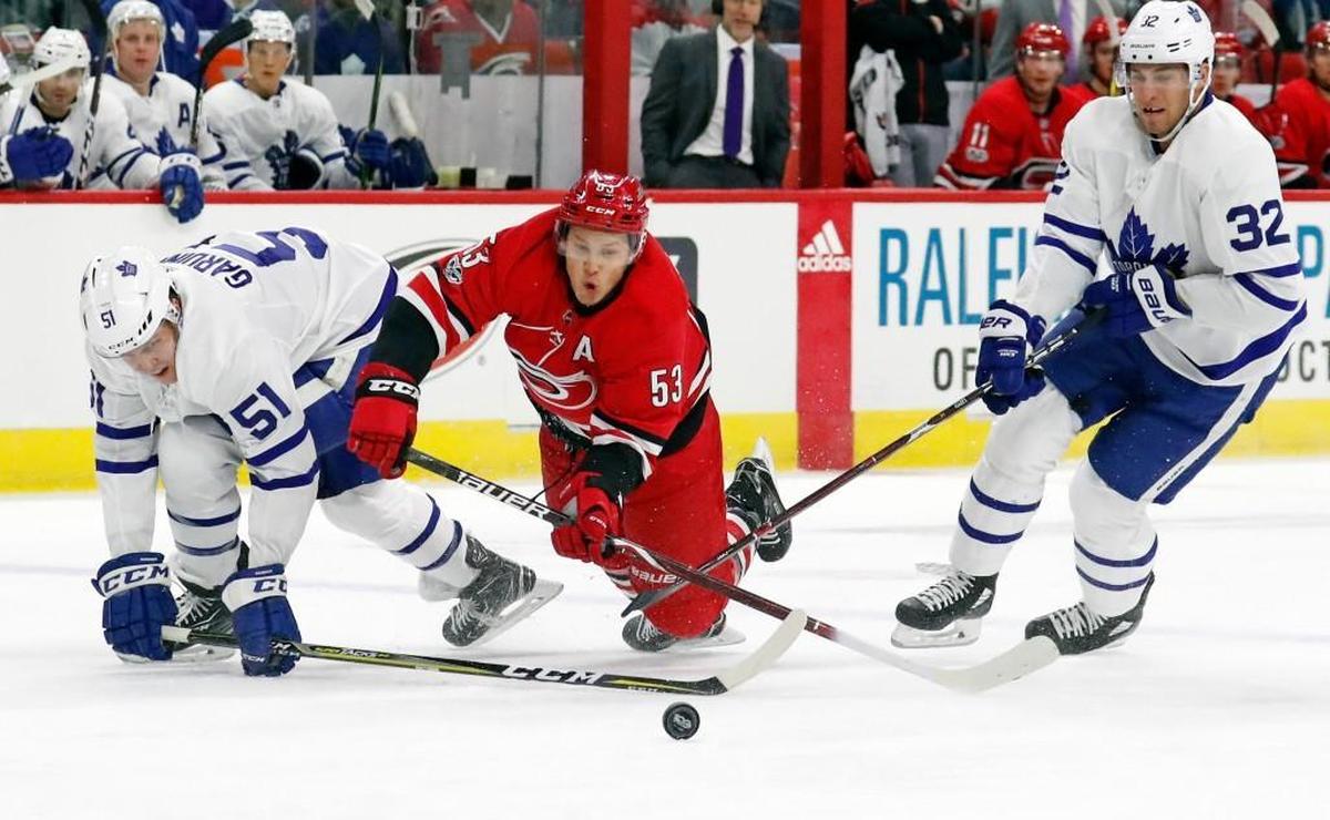 The Canes' Jeff Skinner (53) battles the Leafs' Jake Gardiner (51) and Josh Leivo (32) as they go for the puck during the first period. Toronto was called for a penalty on the play.