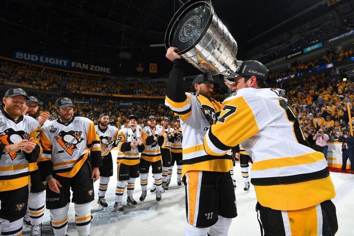 Captain Sidney Crosby of the Pittsburgh Penguins gives the Stanley Cup to teammate Ron Hainsey.
