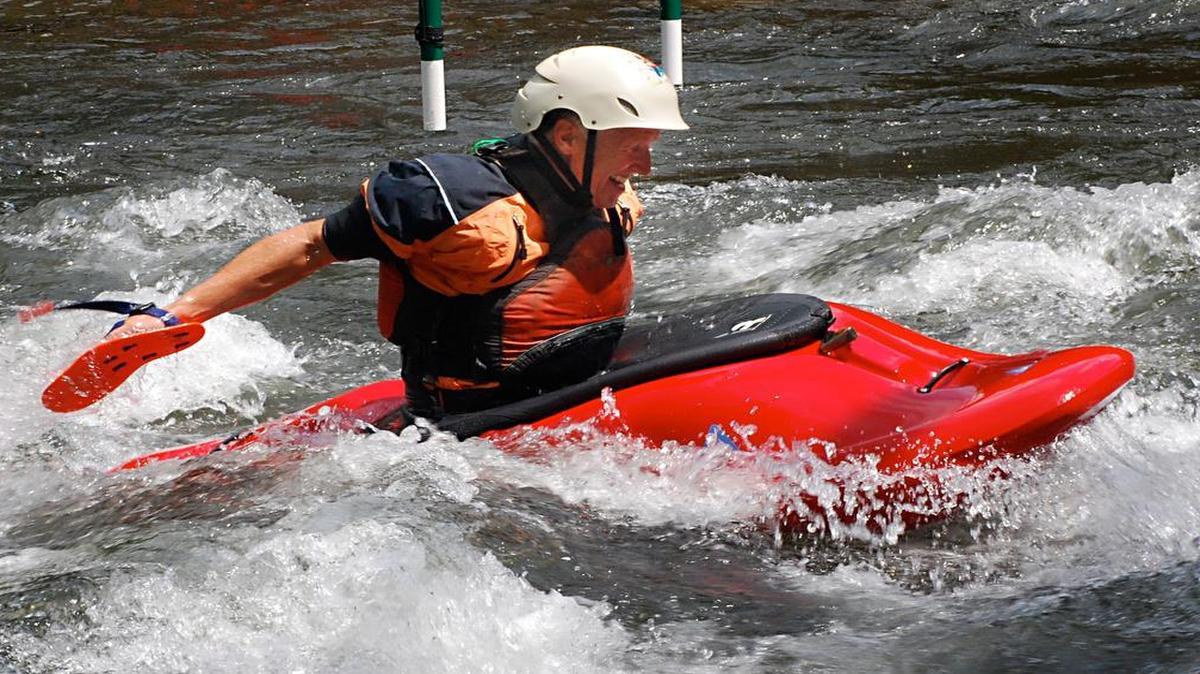 Hand paddler Mike Brown surges through a wave beneath a hanging slalom gate on the Nantahala River at the Nantahala Outdoor Center.