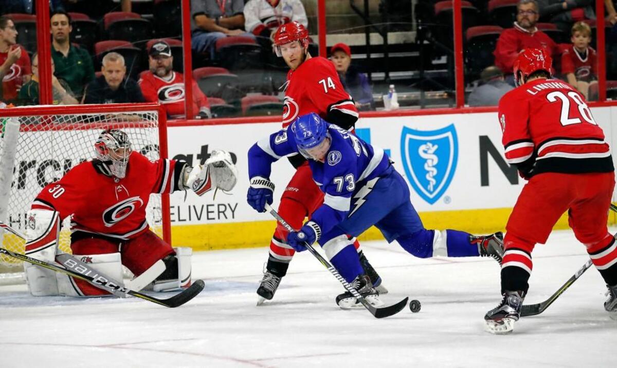 The Canes' Cam Ward (30), Jaccob Slavin (74) and Elias Lindholm (28) defend Tampa Bay's Adam Erne (73).
