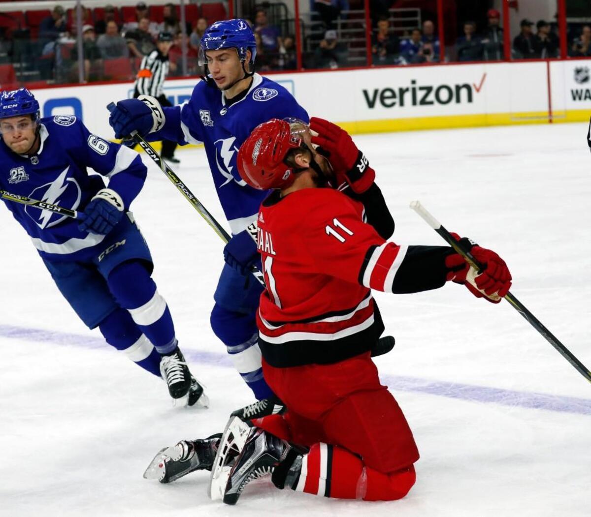 The Canes' Jordan Staal (11) grabs his face and falls to the ice after he got hit in a face-off with Tampa Bay's Anthony Cirelli (71).