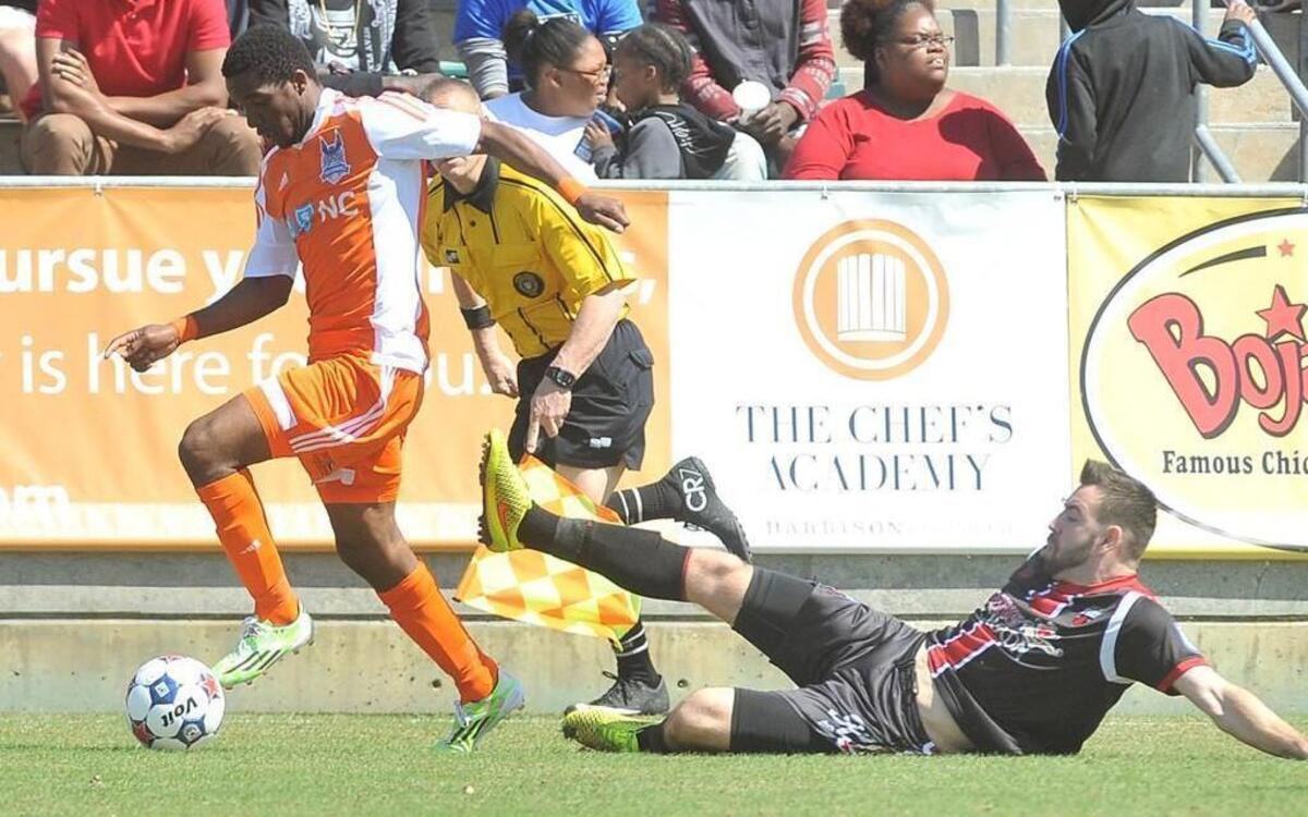 Carolina RailHawks' Tiyi Shipalane (11) sprints away from the attempted slide tackle from Ottawa's Colin Falvey (32) during the second half. The Carolina RailHawks took on the Ottawa Fury in their season opener at the WakeMed Soccer Park in Cary, N.C. on April 4, 2015.