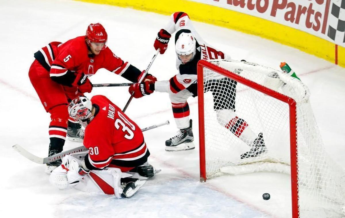 The Devils' Taylor Hall (9) puts the puck past the Canes' Noah Hanifin (5) and Cam Ward (30) for the game-winner in the overtime period an NHL game played between the Carolina Hurricanes and the N.J. Devils at PNC Arena in Raleigh, N.C. on Feb. 18, 2018. The Devils beat the Canes 3-2 in overtime.