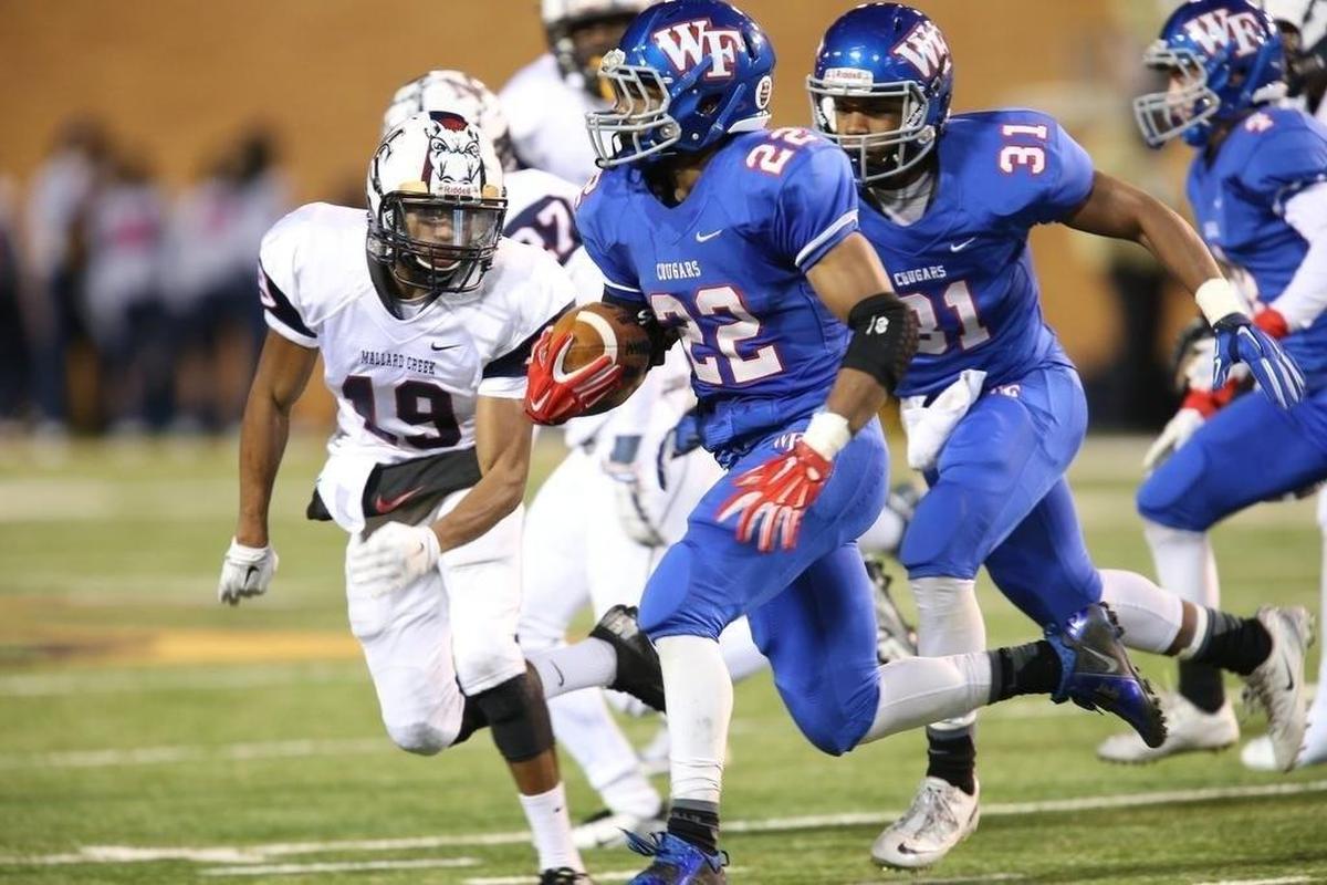 Wake Forest's Bryce Love (22) tries to turn the corner on Mallard Creek's Dezmond Scott (19) 1 during the 4AA NCHSAA Championship game of the Mallard Creek High School Football game against Wake Forest High School, December 13, 2014 in Wake Forest.