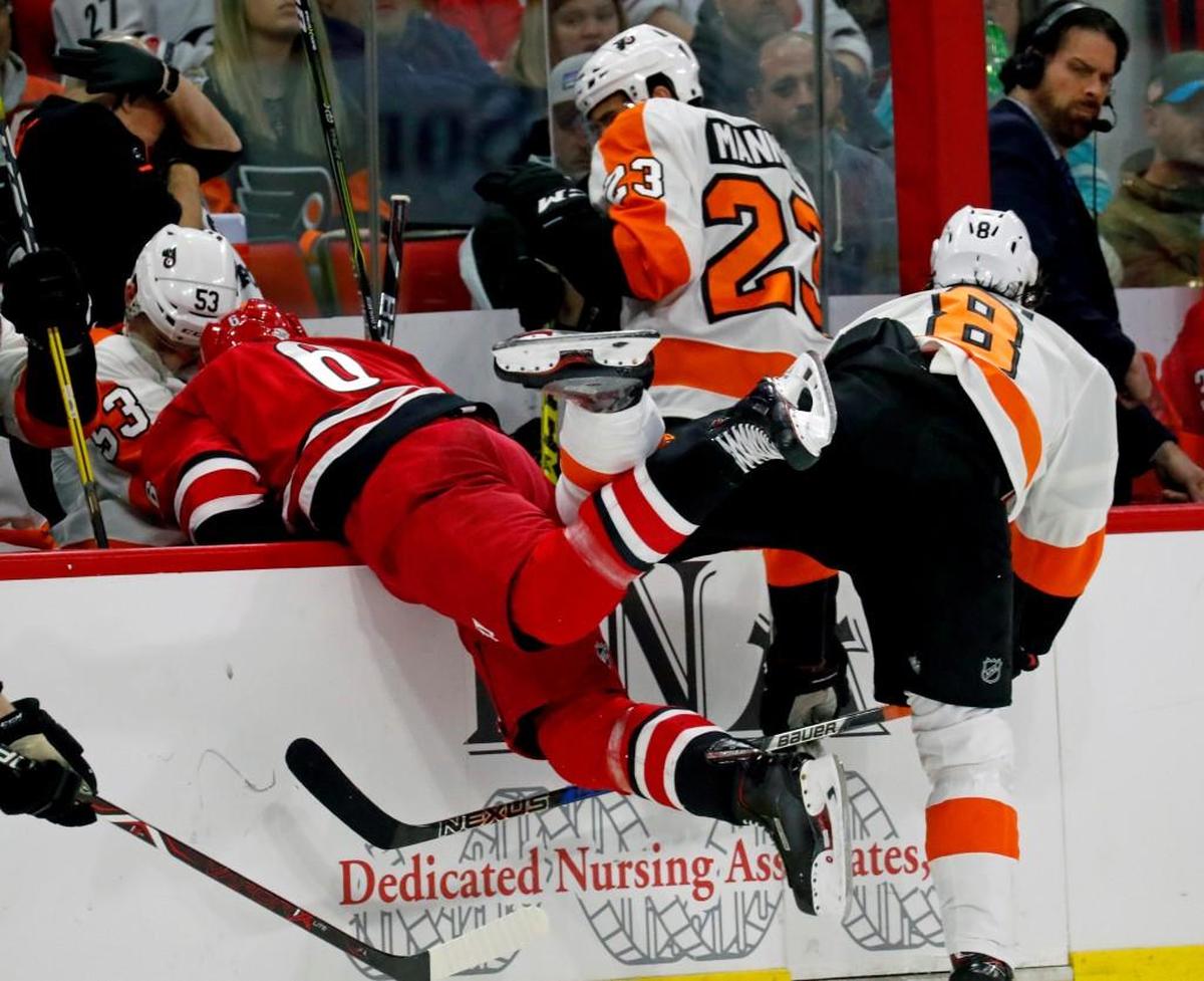 The Canes' Klas Dahlbeck (6) and the Flyers' Robert Hagg (8) tumble into the bench while Brandon Manning (23) tries to get out of the way as they collide during the second period of an NHL game played between the Carolina Hurricanes and the Philadelphia Flyers at PNC Arena in Raleigh, N.C. on Feb. 6, 2018.