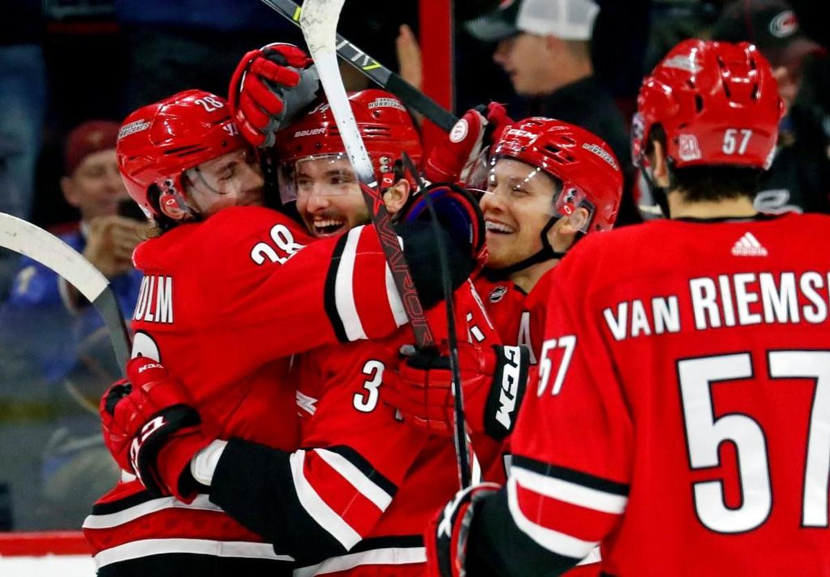 The Canes' Phillip Di Giuseppe (34) celebrates his goal, his first of the season, with Elias Lindholm (28), Jeff Skinner (53) and Trevor van Riemsdyk (57) during the first period of an NHL game played between the Carolina Hurricanes and the Vancouver Canucks on Feb. 9, 2018.