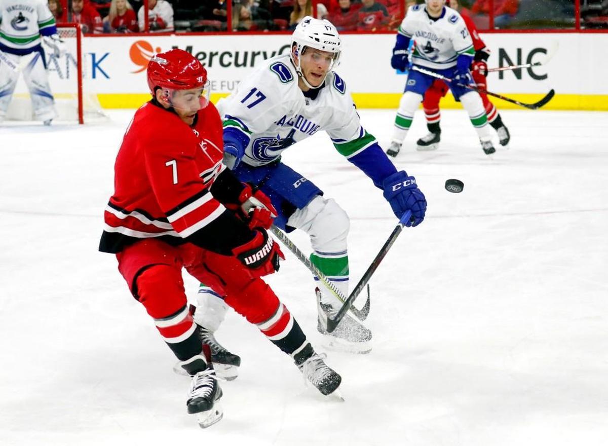 The Canes' Derek Ryan (7) and the Canucks' Nic Dowd (17) battle for a flying puck during an NHL game played between the Carolina Hurricanes and the Vancouver Canucks on Feb. 9, 2018.