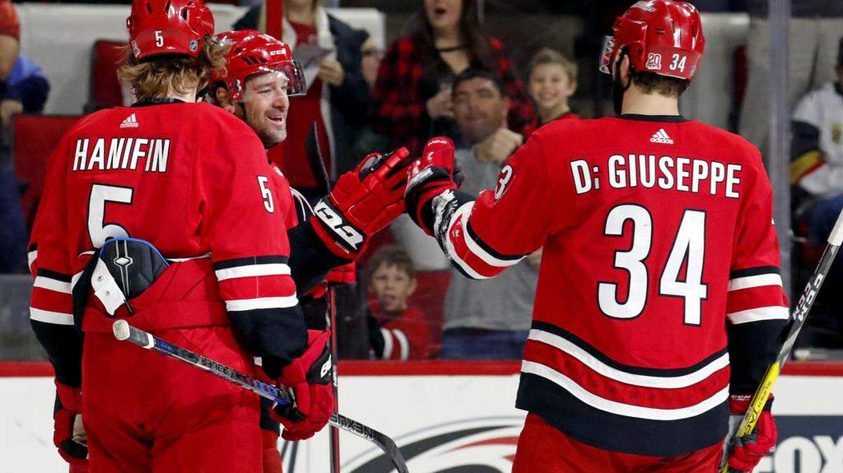 The Canes' Justin Williams (14) celebrates his goal with Noah Hanifin (5) and Phillip Di Giuseppe (34) during the first period of an NHL game played between the Carolina Hurricanes and the Tampa Bay Lightning at PNC Arena in Raleigh, N.C., on April 7, 2018. The Canes won 3-2 in overtime.