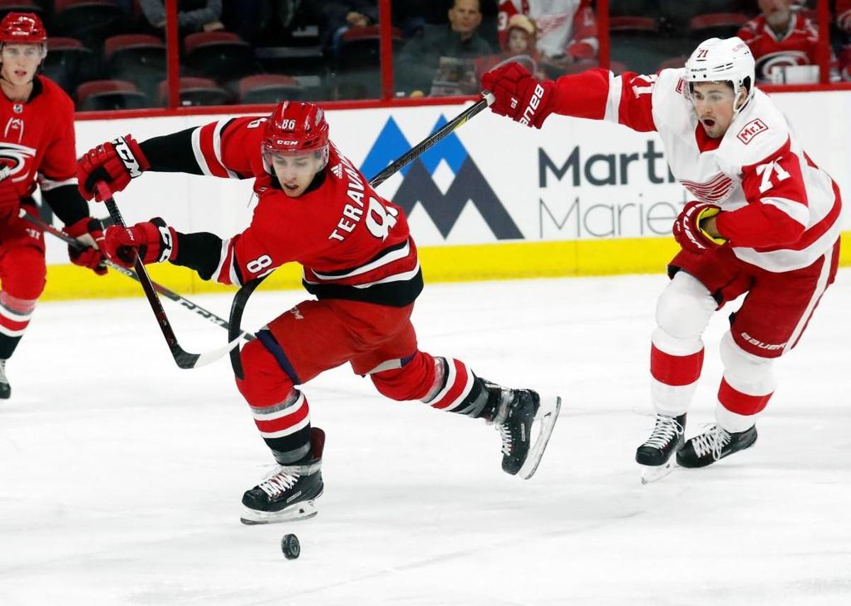 The Canes' Teuvo Teravainen (86) gets hooked by the Red Wings' Dylan Larkin (71) during the first period of an NHL game played between the Carolina Hurricanes and the Detroit Red Wings at PNC Arena in Raleigh on Feb. 2, 2018. Larkin was called for a penalty on the play.