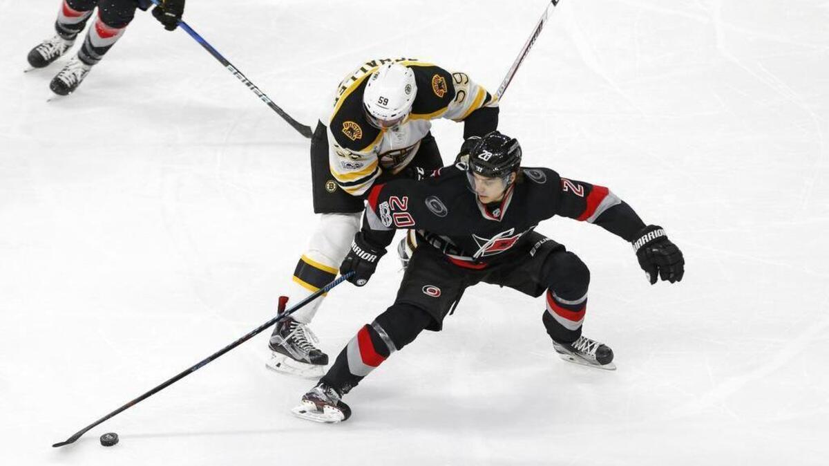 The Canes' Sebastian Aho (20) and the Boston Bruins' Tim Schaller (59) go for the puck during the third period at PNC Arena on Jan. 8, 2017. The Canes beat the Bruins 4-3.
