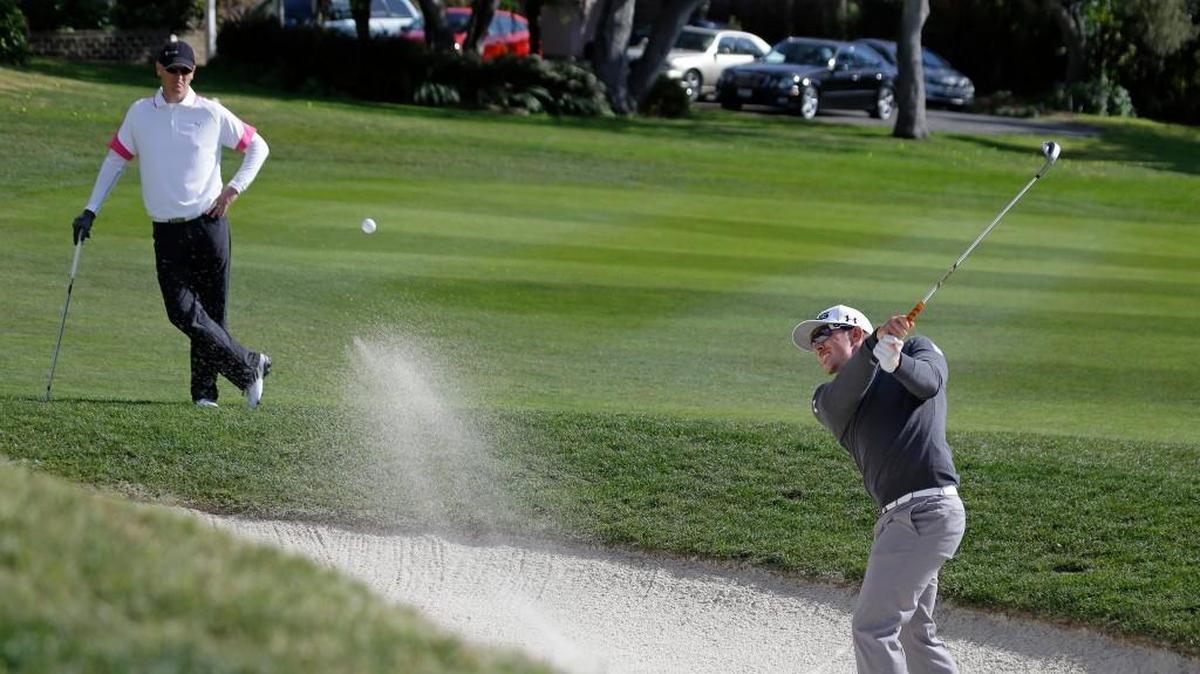 Carolina Hurricanes owner Thomas Dundon, left, watches as Hunter Mahan hits out of a bunker up to the 14th green of the Pebble Beach Golf Links during the first round of the AT&T Pebble Beach Pro-Am golf tournament Thursday, Feb. 7, 2013 in Pebble Beach, Calif. Mahan shot a 6-under-par 66 and tied for the lead. The two will play together in the tournament again this week.