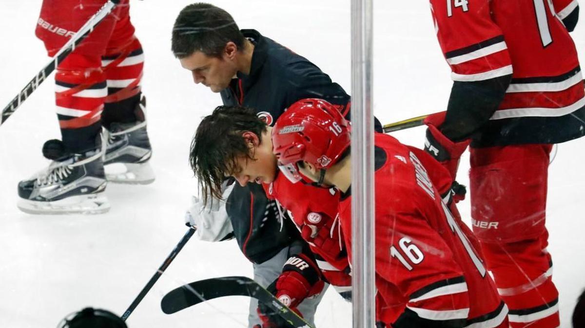 The Canes' Sebastian Aho (20) is helped off the ice by trainer Doug Bennett and Marcus Kruger (16) after getting hit by the Flames Mark Giordano (5) during the third period of an NHL game played between the Carolina Hurricanes and the Calgary Flames at PNC Arena in Raleigh, N.C. on Jan. 14, 2018. Giordano was given a game misconduct penalty. Aho did not return to the game. The Flames beat the Canes 4-1.