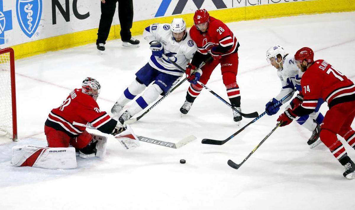 The Canes' Cam Ward (30), Elias Lindholm (28) and Jaccob Slavin (74) defend against the Lightning's J.T. Miller (10) and Brayden Point (21) during the third period.