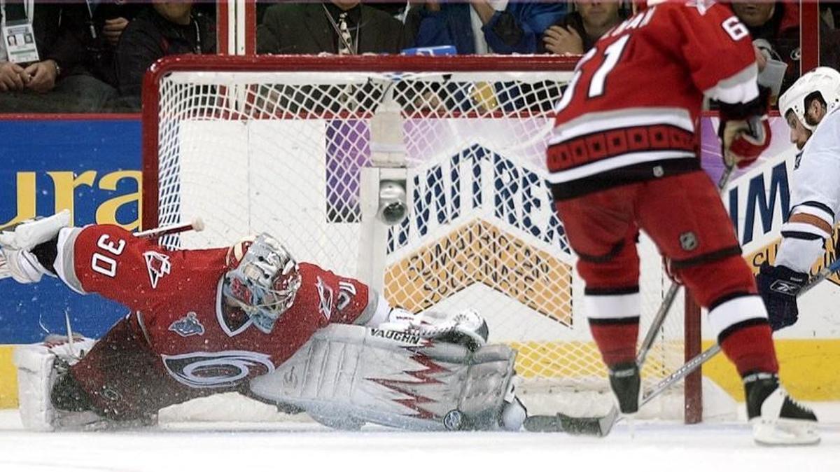 Canes goalie Cam Ward (30) stretches out to make a stop against the Oilers Fernando Pisani (34) as the Canes Cory Stillman (61) looks on in Game 7 of the Stanley Cup Finals on June 19, 2006. The Canes won the game 3-1.
