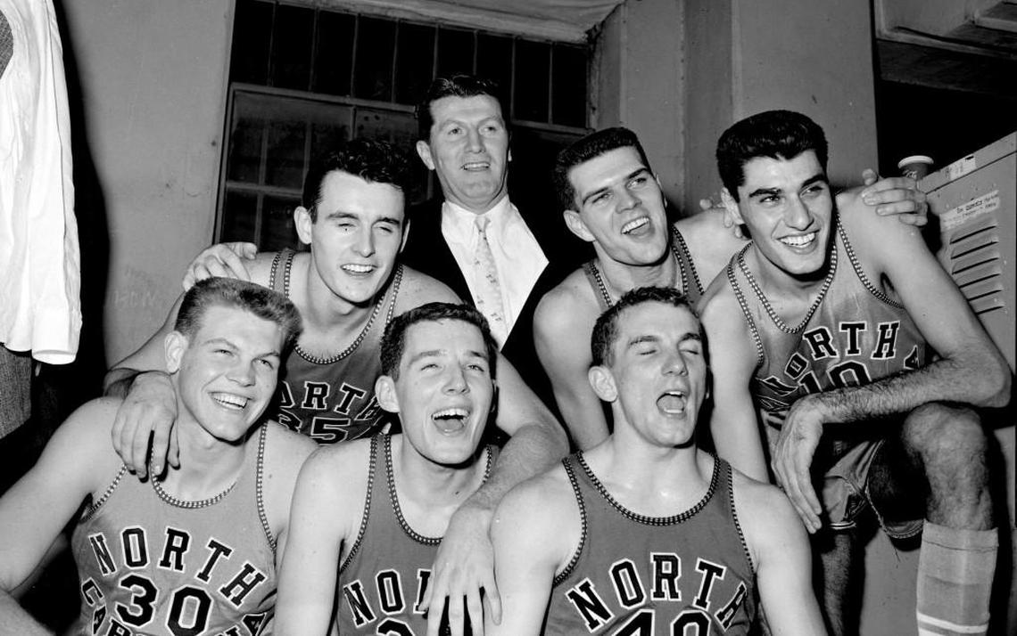 The 1957 Tar Heels pose with coach Frank McGuire in the UNC locker room at the ACC Tournament.