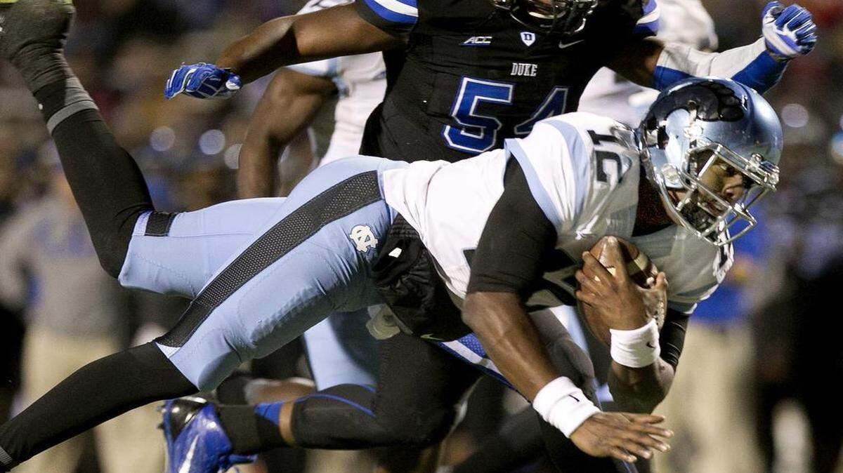 
UNC quarterback Marquise Williams (12) rushes for 12 yards to the four yard line to set up the Tar Heels' first touchdown in the first quarter ahead of Duke's C.J. France (54) on Thursday, November 19, 2014 at Wallace Wade Stadium in Durham, N.C.

