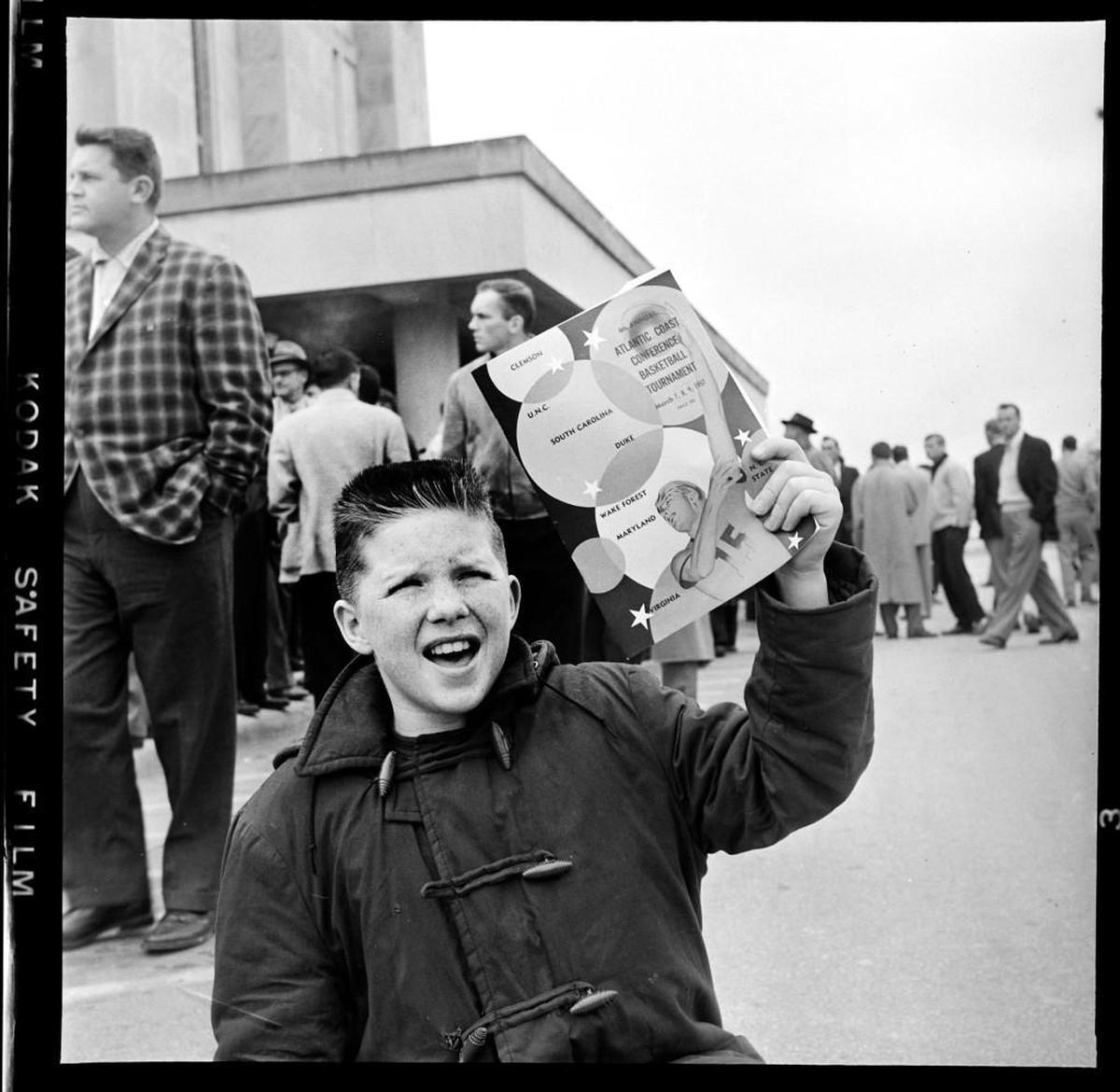 A boy hawks programs for the 1957 ACC Tournament while standing outside of Reynolds Coliseum in Raleigh.