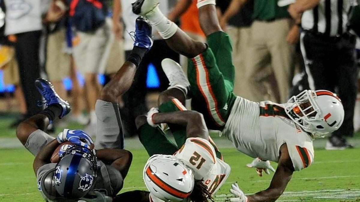 Duke's Johnathan Lloyd (5) battles Miami's Malek Young (12) and Jaquan Johnson (4) for a first down Friday in Wallace Wade Stadium.