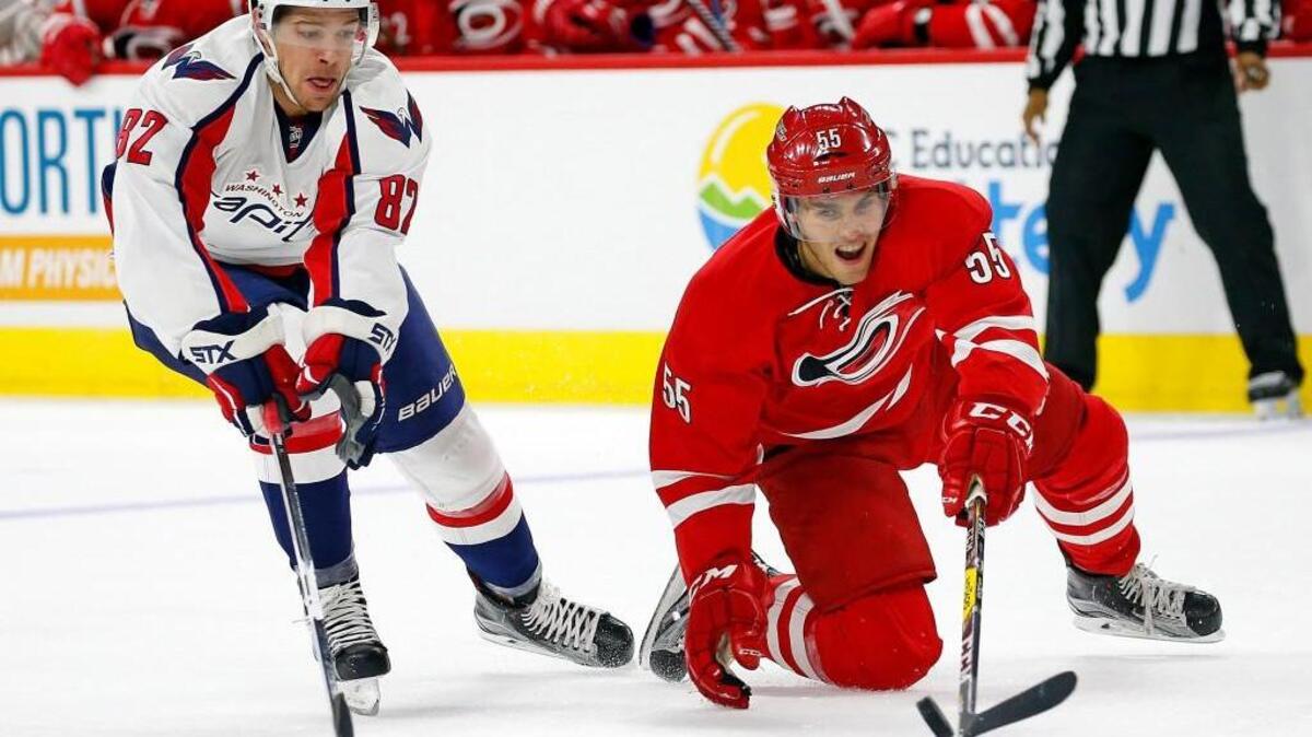 The Carolina Hurricanes' Roland McKeown (55) tries to control the puck in front of the Washington Capitals' Zachary Sanford (82) during the first period.