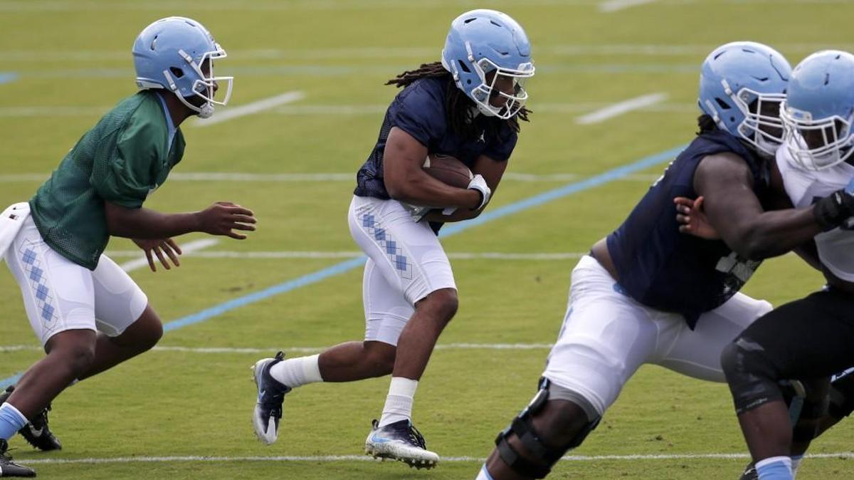 Running back Jordan Brown (2), center, runs through a drill after getting a handoff from QB Brandon Harris (6) as the UNC Tar Heels hold football practice at Kenan Stadium in Chapel Hill on August 2, 2017.