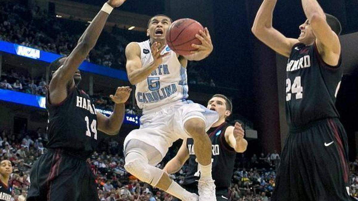 
North Carolina’s Marcus Paige drives to the basket between Harvard’s Steve Moundou-Missi (14) and Jonah Travis (24) for two of his 12 points during the second half of their second round game in the NCAA Tournament on Thursday, March 19, 2015, in Jacksonville, Fla.
