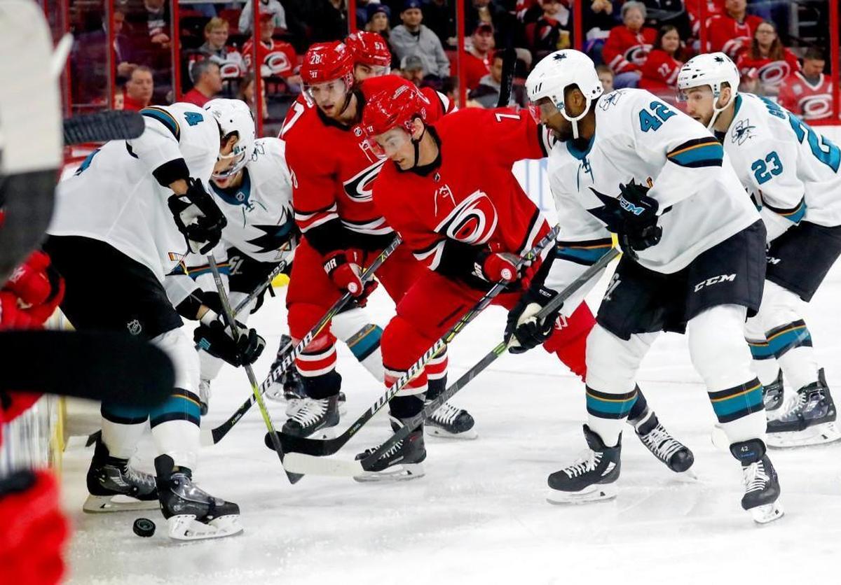 The Canes' Elias Lindholm (28) and Derek Ryan (7) battle the Sharks' Brenden Dillon (4), Joel Ward (42) and Barclay Goodrow (23) for the puck along the boards during the first period of an NHL game played between the Carolina Hurricanes and the San Jose Sharks at PNC Arena in Raleigh, N.C. on Feb. 4, 2018.