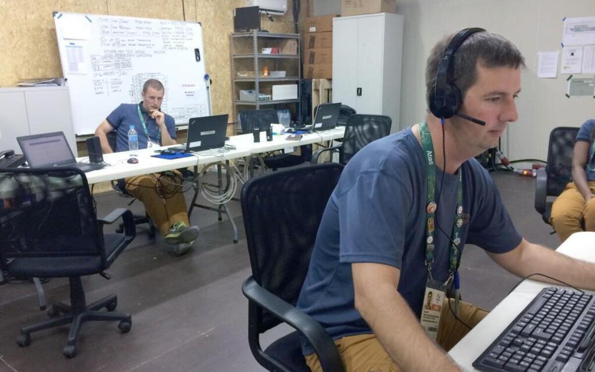 Jonathan Tew, left, and Rusty Knott work inside the control room where they have spent the Olympics. There are monitors, workstations, racks of equipment and white boards, but mostly there’s plywood, fresh enough to exude a powerful chemical smell.