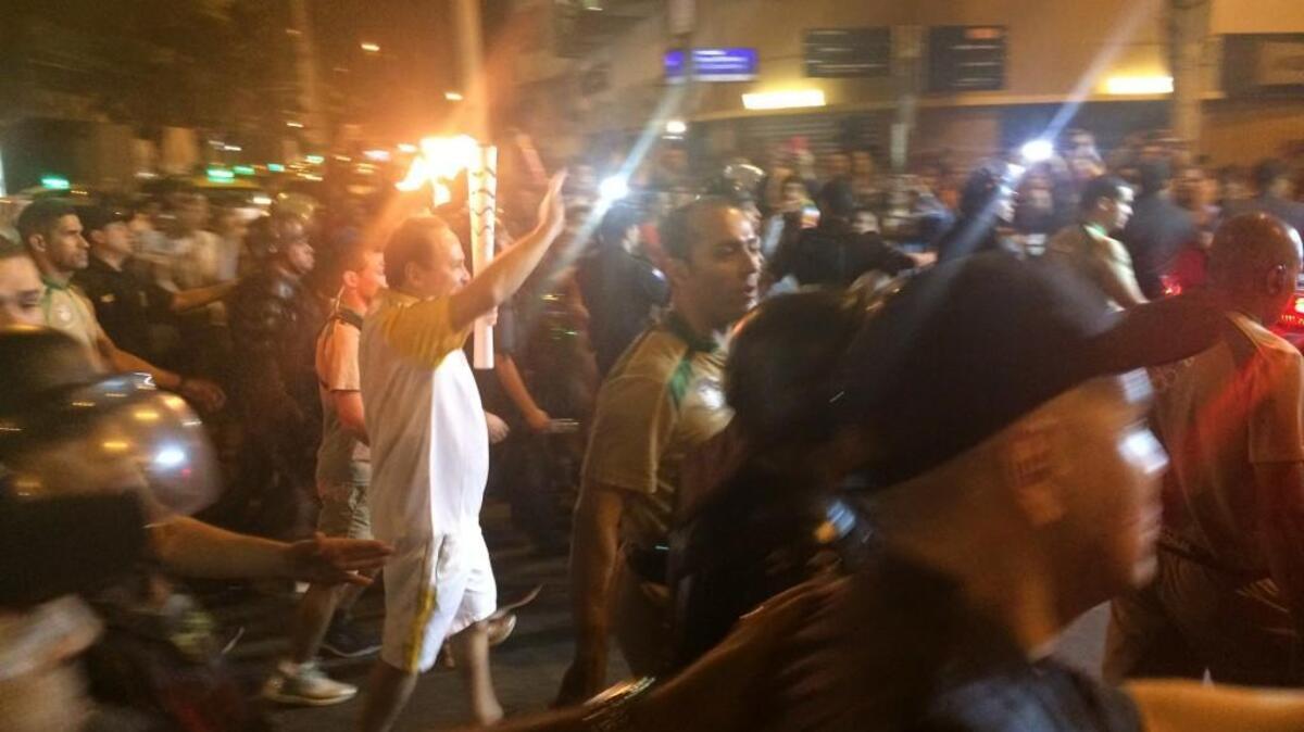 The Olympic torch relay makes its way through a massive crowd on the streets of Copacabana just after midnight Friday morning.