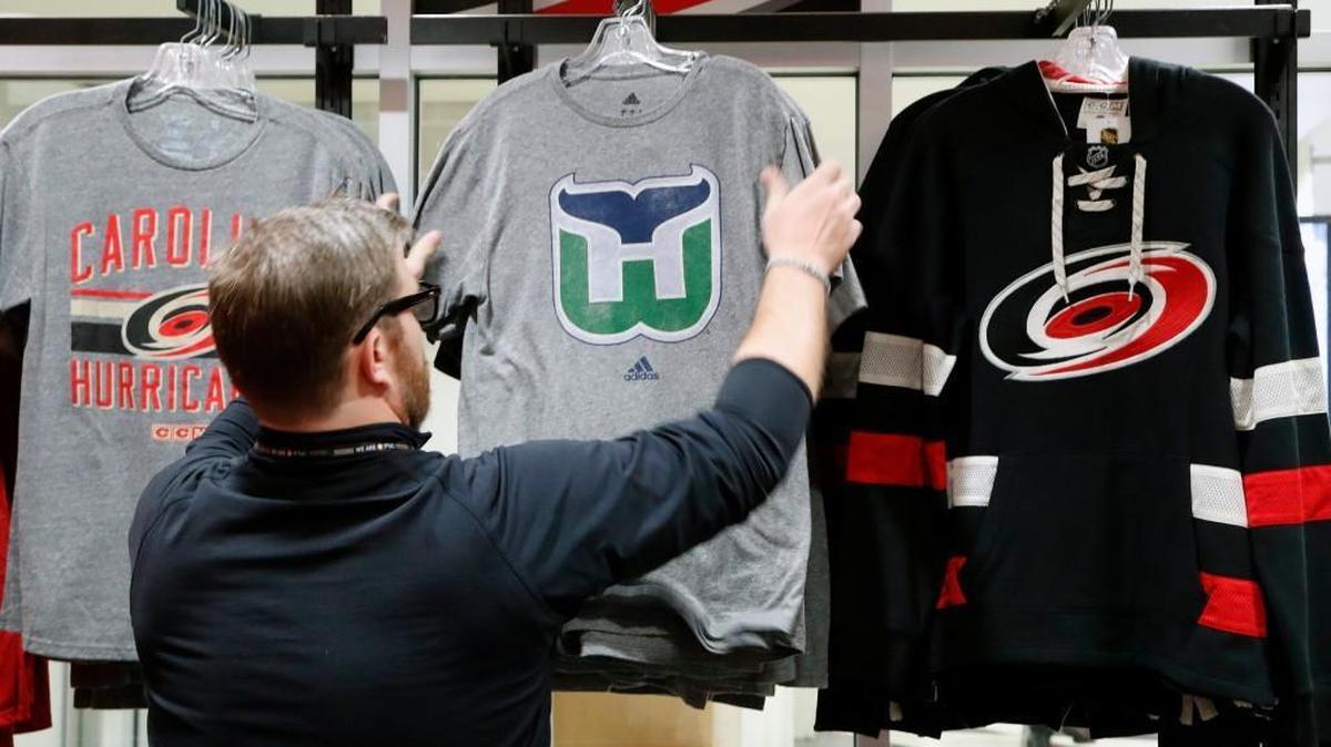 Kurt Cusac, a worker at The Eye store, straightens out the Hartford Whalers tee shirts before the doors open before an NHL game played between the Carolina Hurricanes and the Montreal Canadiens at PNC Arena in Raleigh, N.C. on Feb. 1, 2018. It’s the first time items from the team’s former identity are being sold, a change brought about by the Canes’ new owner, Tom Dundon.